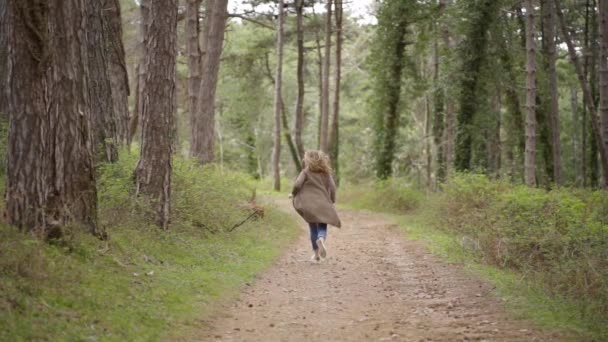 Une jeune fille avec un sac à dos courant à travers la forêt — Video