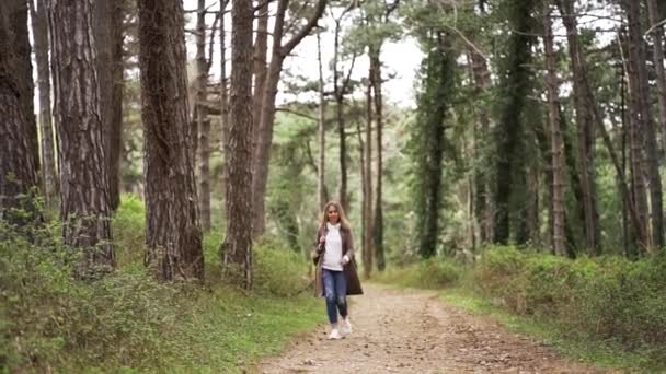 Une jeune fille avec un sac à dos courant à travers la forêt — Video
