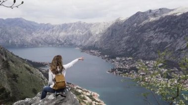 Karadağ 'da bir dağın tepesinde sırt çantalı bir kız oturuyor