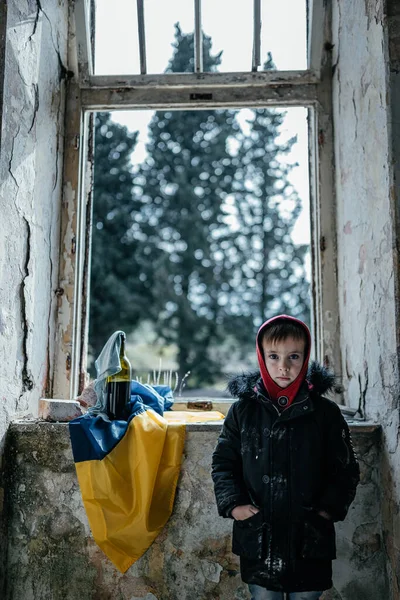 Kleiner Junge in einem zerstörten Haus Krieg in der Ukraine ukrainische Flagge — Stockfoto