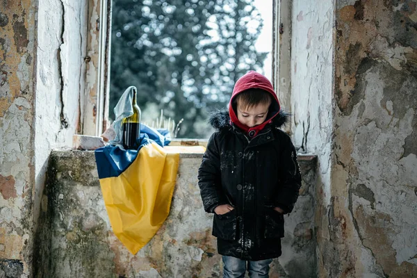 Μικρό αγόρι σε ένα κατεστραμμένο πόλεμο σπίτι στην Ουκρανία ουκρανική σημαία — Φωτογραφία Αρχείου