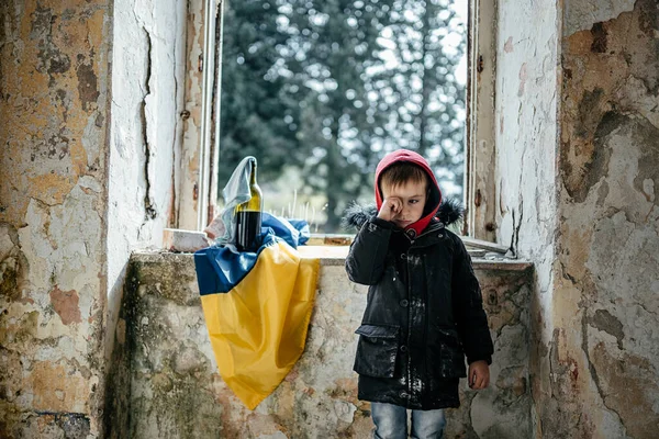 Liten pojke i ett förstört hus krig i Ukraina Ukrainska flagga Royaltyfria Stockbilder