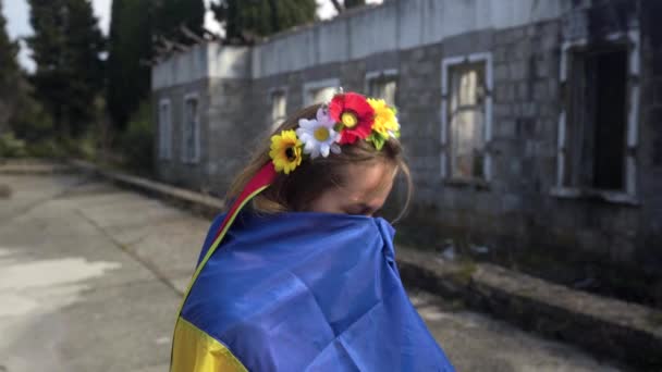 Chica ucraniana llora cerca de la casa destruida bandera de Ucrania — Vídeos de Stock