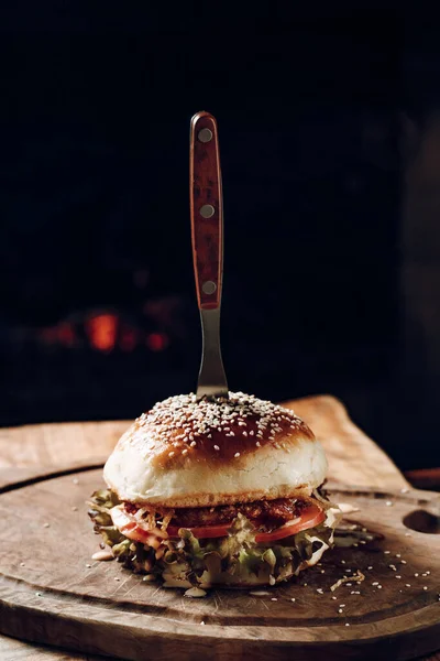 Siyah bir arka planda tahta bir stantta sulu bir hamburger.