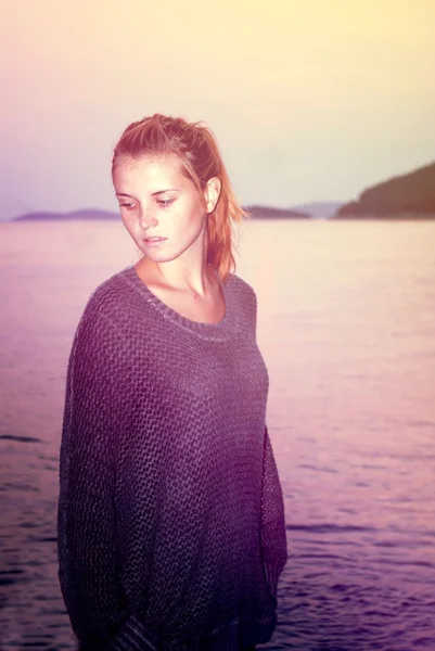 Beautiful woman in sweater comes in the sea, cross process — Stock Photo, Image