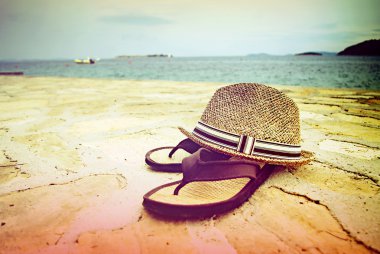 Beach sandals and straw hat by the sea, Croatia Dalmatia clipart