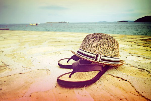 Пляжные сандалии и соломенная шляпа у моря, Хорватия Далмация
