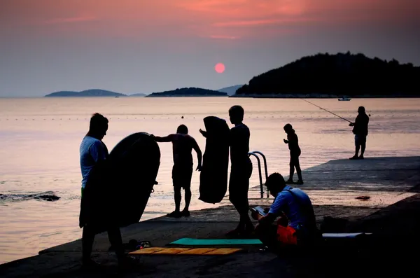 Silhuetas de na praia, mar com pôr do sol Croácia Dalmácia — Fotografia de Stock