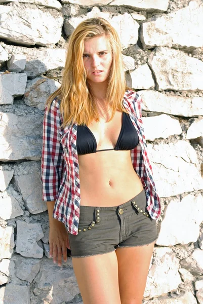 Young woman posing in front of stone wall — Stock Photo, Image