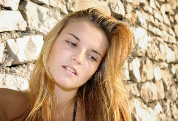 Portrait of attractive young woman posing in front of stone wall — Stock Photo, Image