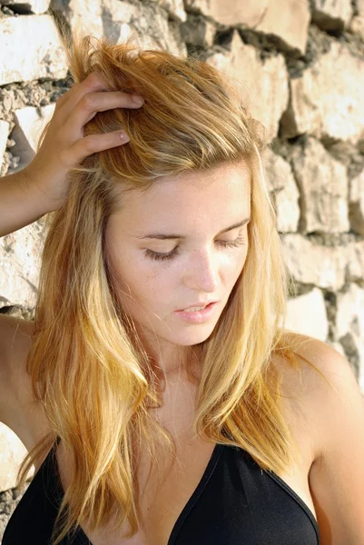 Portrait of attractive young woman posing in front of stone wall — Stock Photo, Image