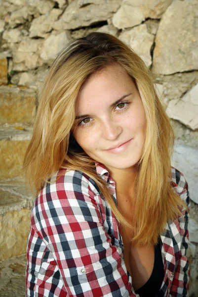 Portrait de jolie jeune femme posant devant un mur de pierre — Photo