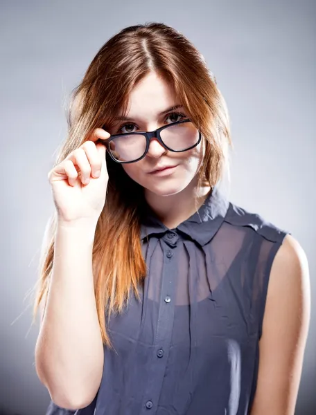 Estricta mujer seria joven sosteniendo gafas nerd — Foto de Stock