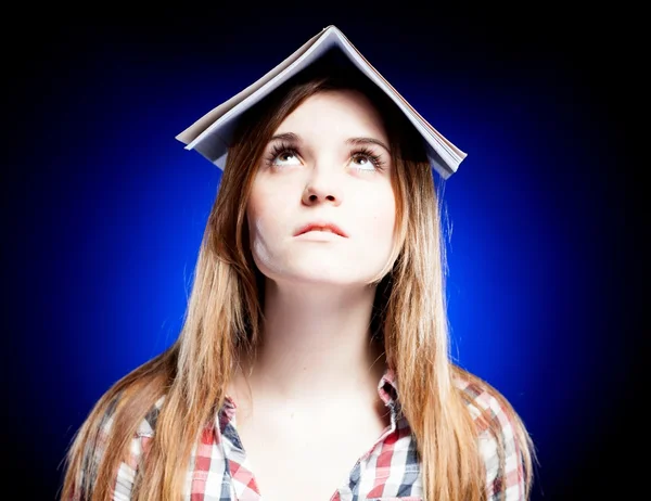 Confused and upset young girl holding exercise book on her head — Stock Photo, Image