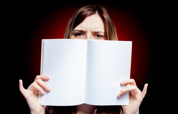 Disappointed and sad young girl holding exercise book