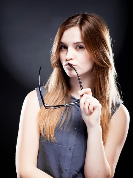 Jonge vrouw bijten een nerd bril met interesse look — Stockfoto