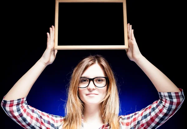 Woman with nerd glasses holding wooden frame over her head — Stock Photo, Image