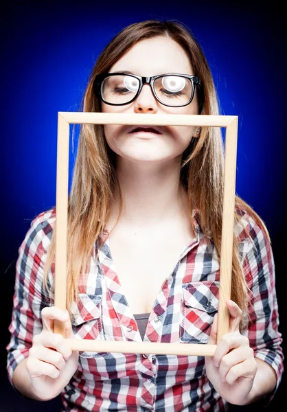 Mulher com óculos nerd olhando para baixo segurando moldura de madeira — Fotografia de Stock