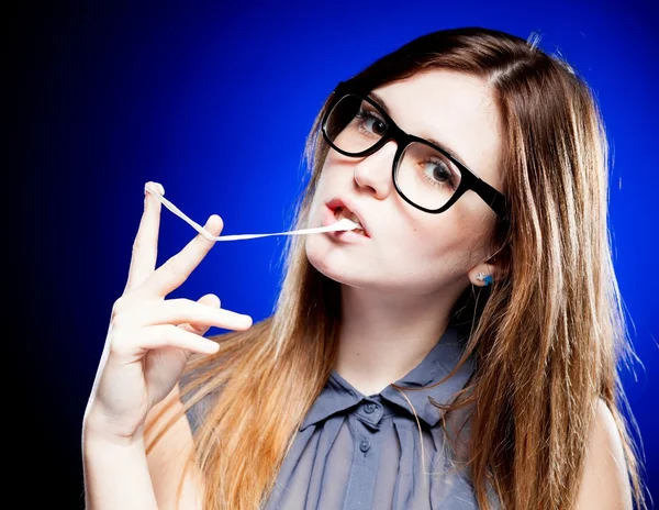 Portrét přísné mladé ženy s brýlemi blbeček a žvýkačky — Stock fotografie
