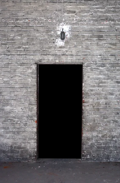 Brick wall and open door, black background — Stock Photo, Image