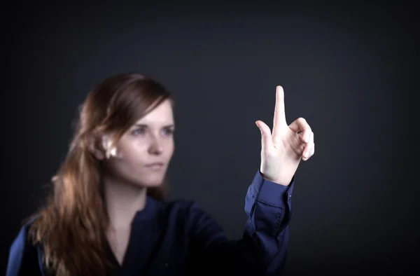 Woman with raised hand and one finger dark background — Stock Photo, Image