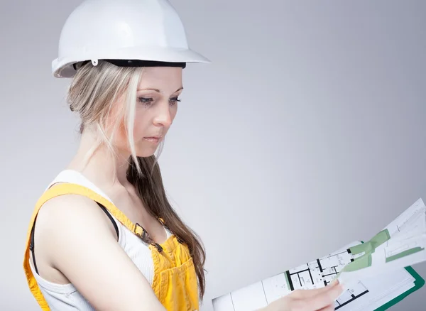 Joven arquitecta trabajadora de la construcción leyendo planos —  Fotos de Stock