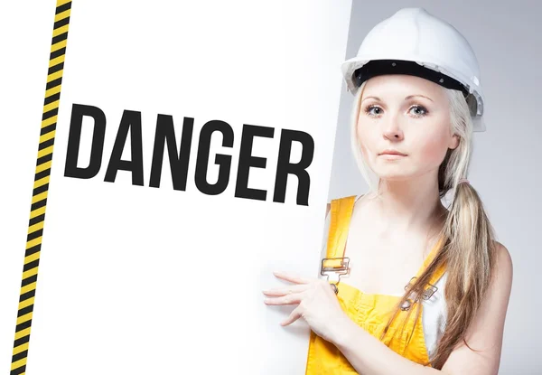 Trabalhador segurando sinal de perigo no painel de informações — Fotografia de Stock