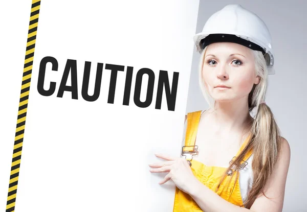 Worker holding caution sign on information board — Stock Photo, Image