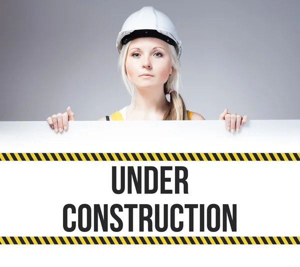 Worker holding under construction sign on information board — Stock Photo, Image