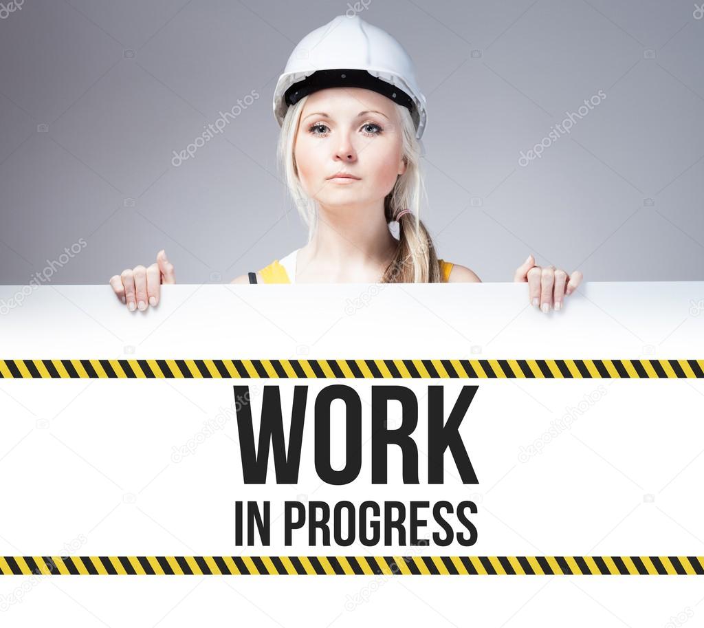 Worker holding work in progress sign on information board