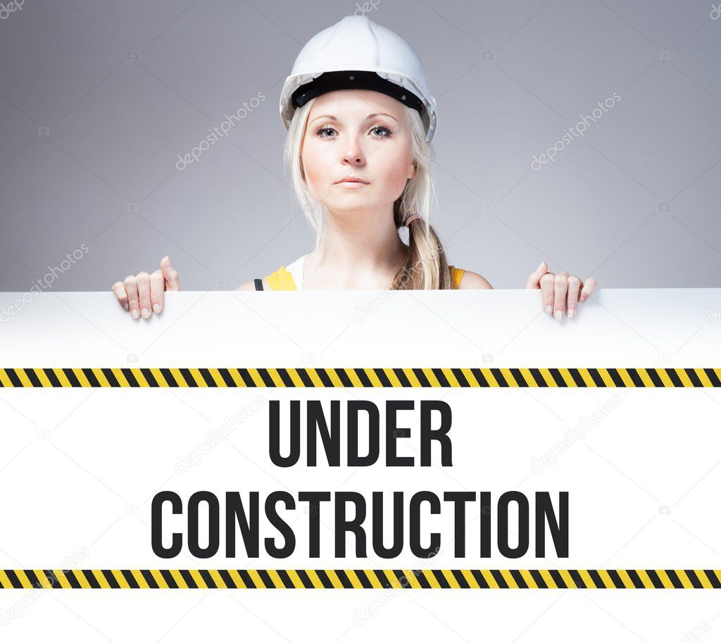 Worker holding under construction sign on information board