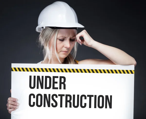 Under construction sign on information board, thinking worker