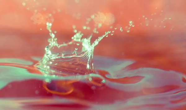 Water Splash Makro Nahaufnahme, roter Hintergrund — Stockfoto