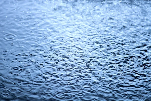 Chuva cai na água de perto, fundo — Fotografia de Stock