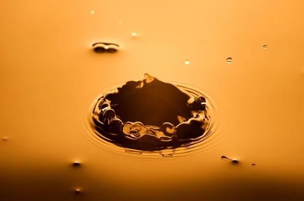 Wasserspritzer Nahaufnahme mit Tropfen, orangefarbener Hintergrund — Stockfoto