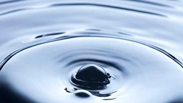 Воды брызги близко с рябью, синий фон — стоковое фото