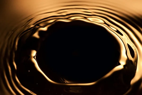 Plusk wody z bliska z zmarszczki, pomarańczowe tło — Zdjęcie stockowe