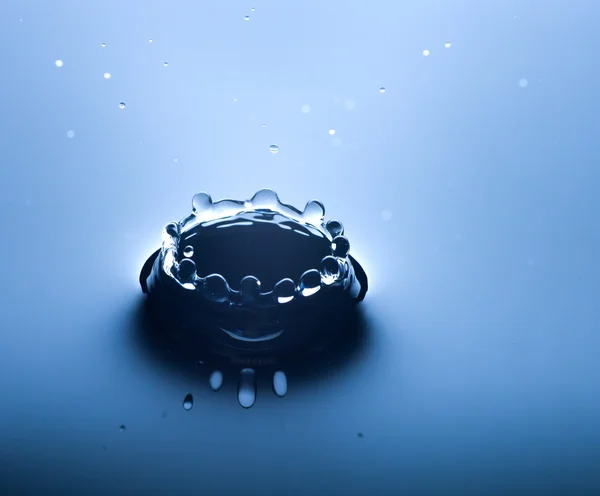 Salpicadura de agua de cerca con gotas, fondo azul —  Fotos de Stock