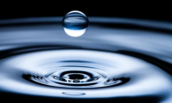 Gota de agua y salpicadura de cerca, color azul oscuro — Foto de Stock