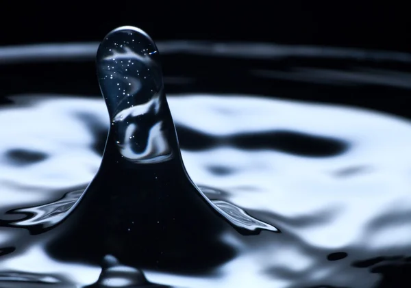 Gota de água e respingo de perto, cor azul escuro — Fotografia de Stock