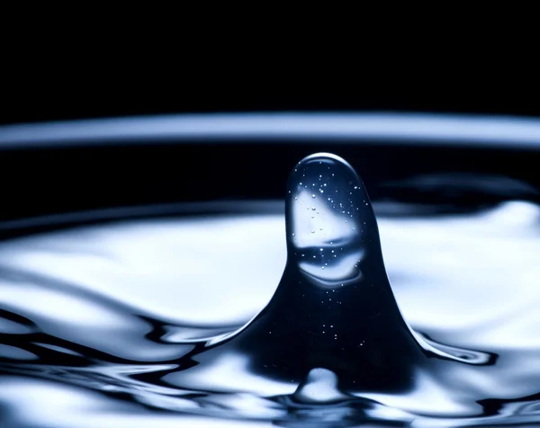 Kapka vody a splash blízko nahoru, tmavě modrá barva — Stock fotografie