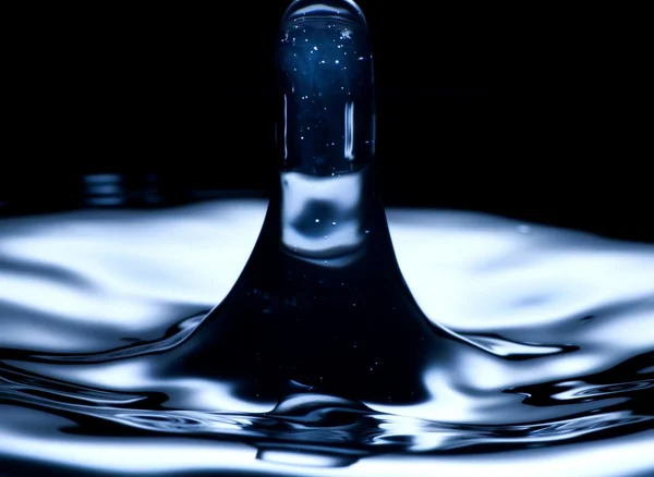 Kapka vody a splash blízko nahoru, tmavě modrá barva — Stock fotografie