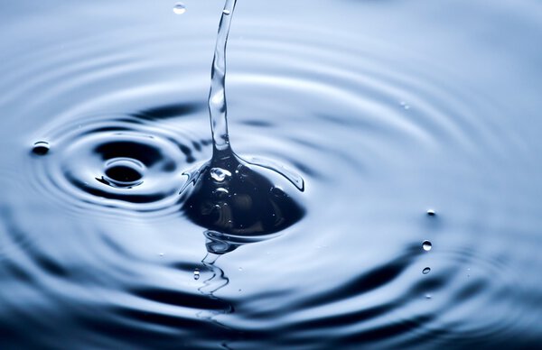 Water drop close up, clear blue background