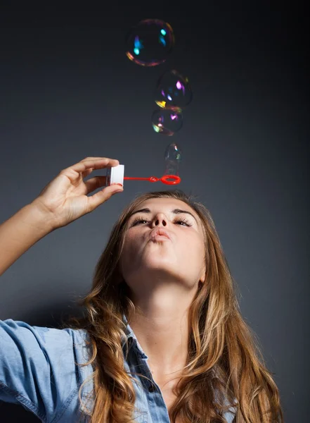 Schöne junge Mädchen weht Seifenblasen, dunklen Hintergrund — Stockfoto