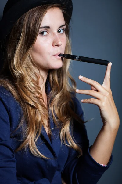 Elegante mujer sosteniendo y fumando cigarrillo electrónico —  Fotos de Stock