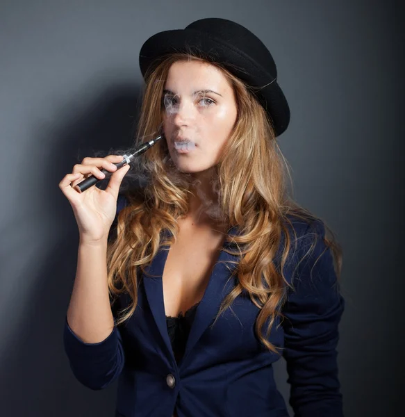 Mulher elegante fumar e-cigarro com fumaça vestindo terno e chapéu — Fotografia de Stock