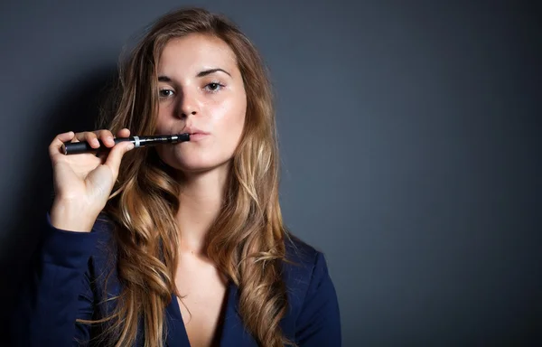 Elegante mujer fumando e-cigarrillo usando traje —  Fotos de Stock