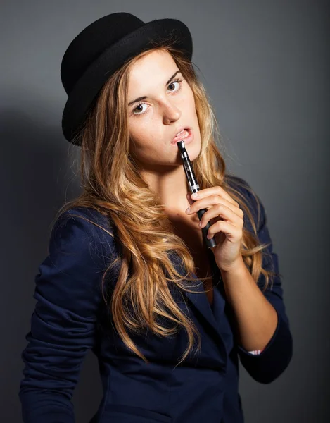 Femme élégante fumant e-cigarette portant costume et chapeau — Photo
