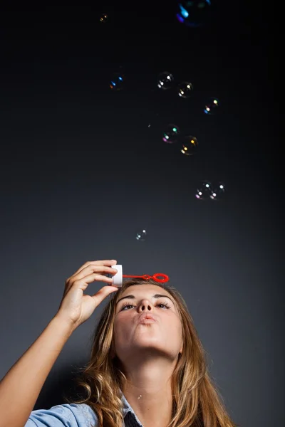 Beautiful young girl blowing soap bubbles, copyspace — Stock Photo, Image