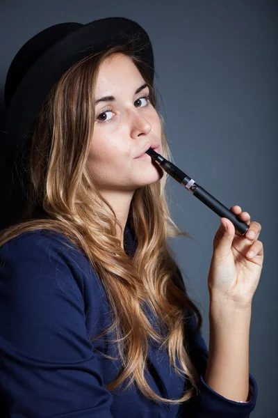 Элегантная женщина держит и курит электронную сигарету — стоковое фото